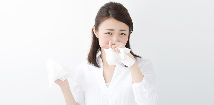 鼻をかむ花粉症の女性