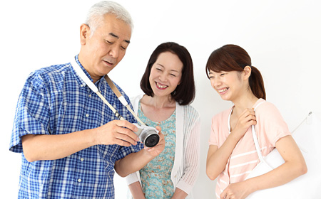 ミラーレス一眼カメラを持つ父親を囲む家族