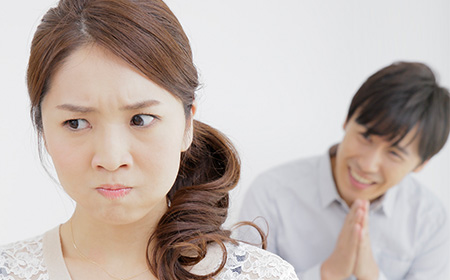 頬をふくらませた女性と謝る男性
