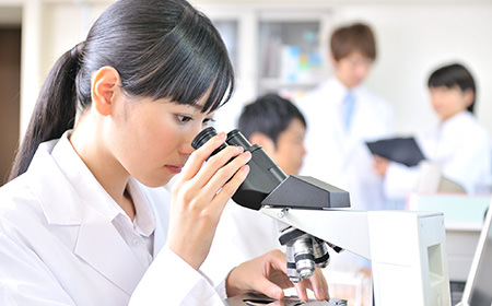 顕微鏡を覗き込む白衣の女性