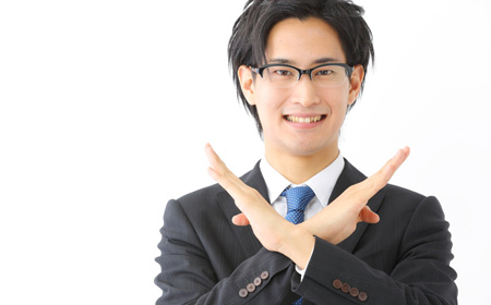 両手でバツ印をするスーツ姿の男性